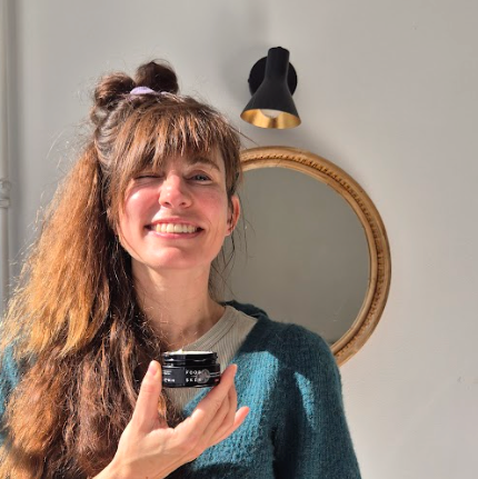 Vrouw houdt een pot crème vast bij een spiegel