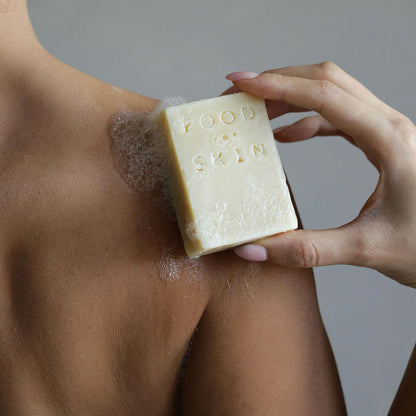 Hand wrijft een body bar over een schouder