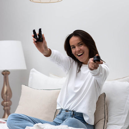 Vrouw zit op bed en houdt drie serums omhoog